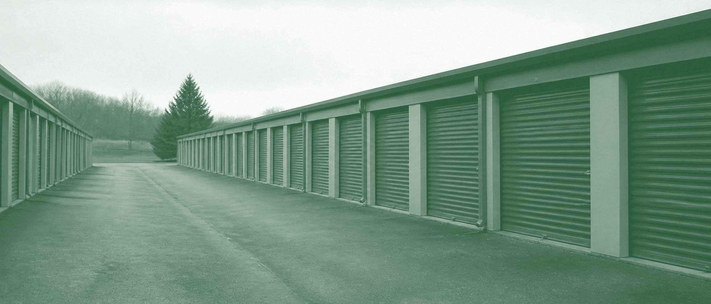 A row of self-storage units with roll-up doors along an empty drive lane